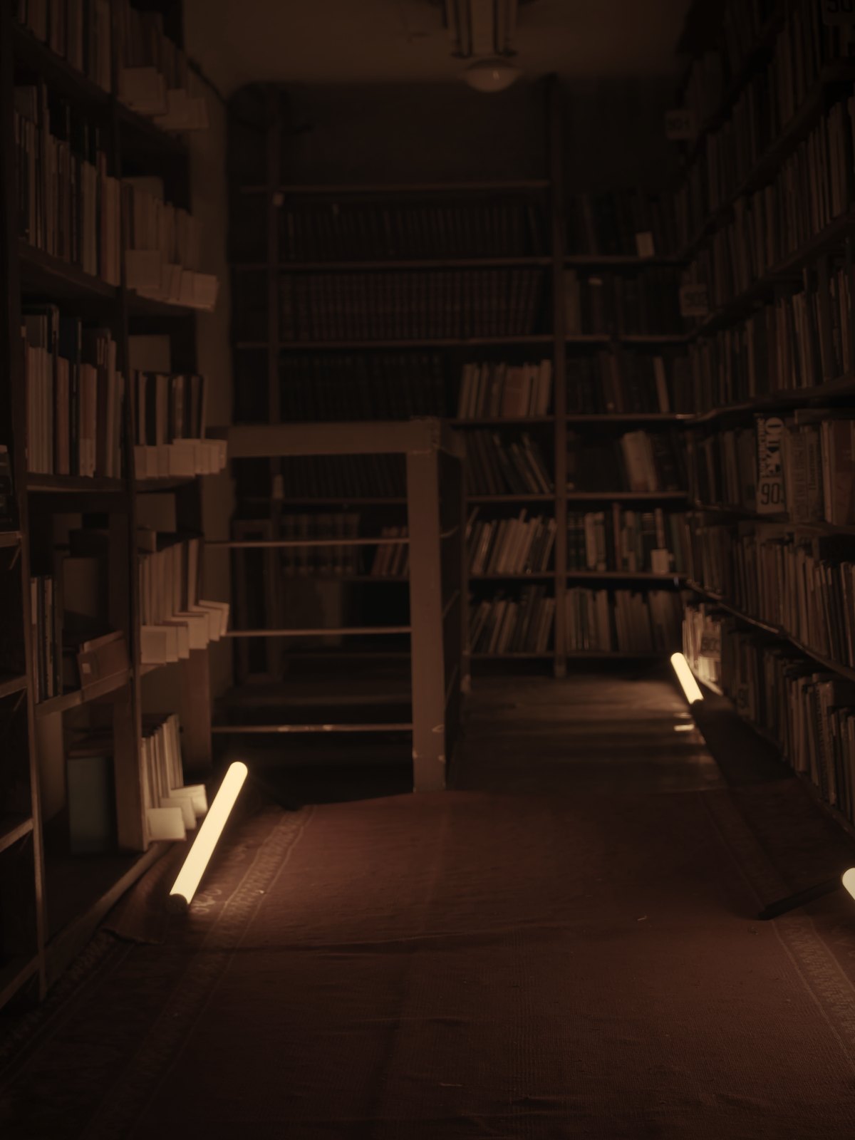 Shelves of worn notebooks and manuals under a single reading lamp.